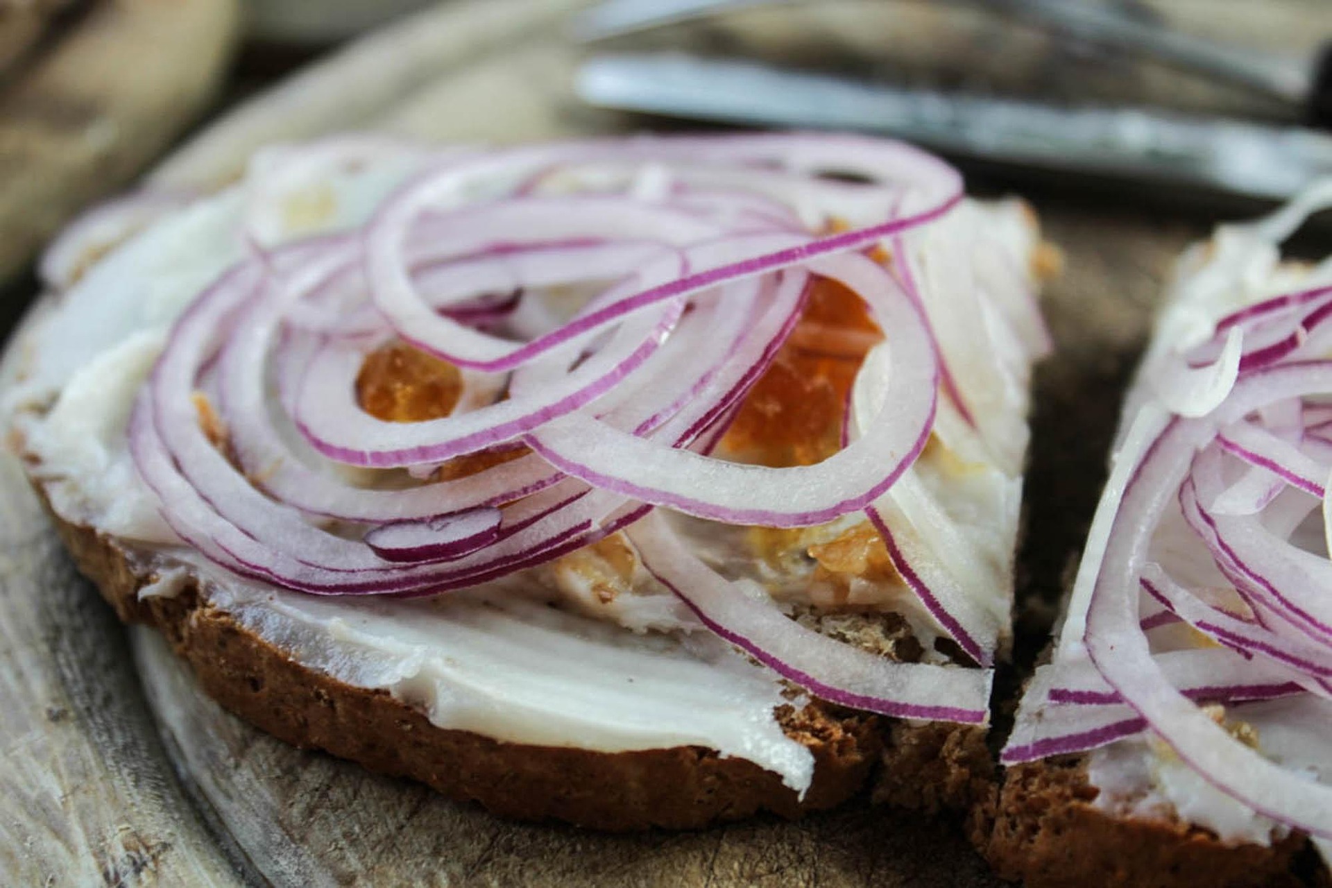 Frisches Schmalzbrot mit roten Zwiebelringen auf rustikalem Holz